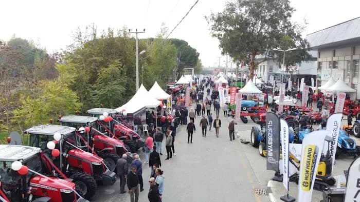 Açık alanda sıra sıra traktörler ve stantlar arasında yürüyen ziyaretçiler